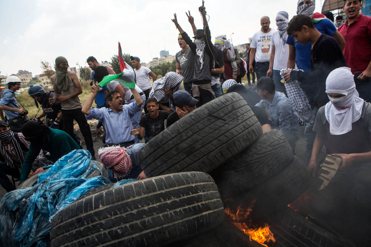 Palestinians shout slogans and burn tires during clashes for Nakba Day near Beit El settlement.