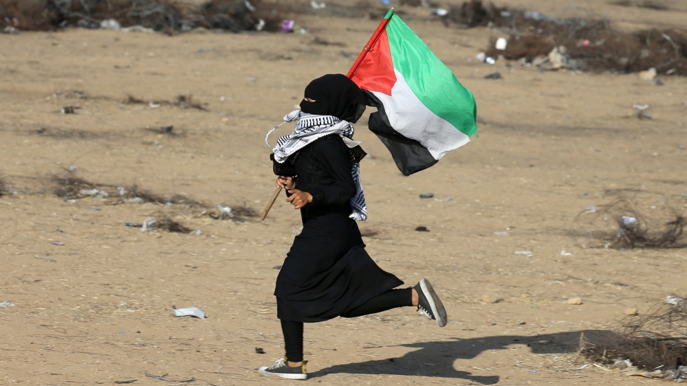 Palestinian girl runs with a Palestinian flag during a protest at the Israel-Gaza border in the southern Gaza Strip
