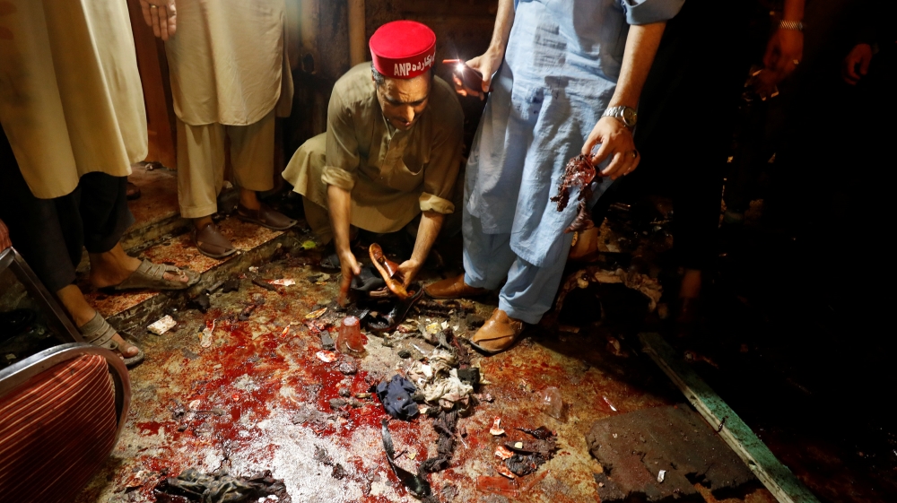 A man collects sandals of people who were killed after a suicide attack during an election campaign meeting in Peshawar