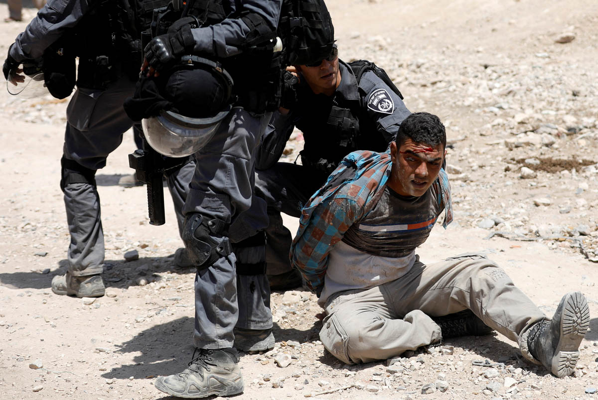 Israeli policemen detain a Palestinian in the Bedouin village of al-Khan al-Ahmar near Jericho in the occupied West Bank July 4, 2018. REUTERS/Mohamad Torokman