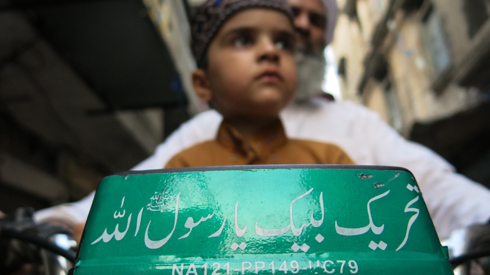 A young boy sits on a motorcycle at a TLP rally in the eastern city of Lahore [Asad Hashim/Al Jazeera]