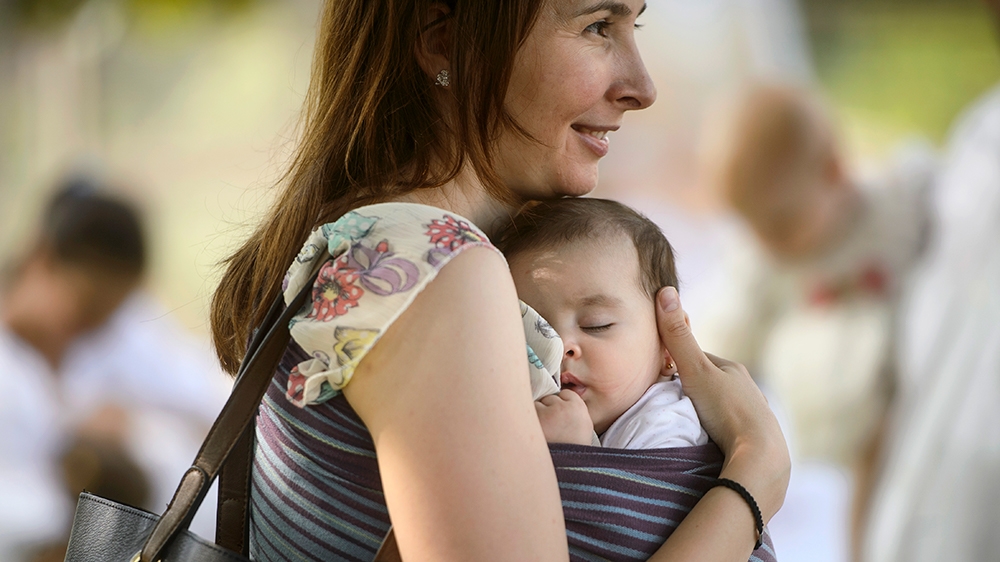 A woman holds her child at an event promoting the freedom of mothers to breastfeed in public, during World Breastfeeding Week at the Village Museum in Bucharest, Romania, Saturday, Aug. 6, 2016. (AP P