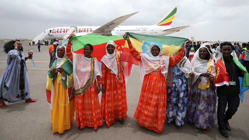 Passengers carry the Ethiopian and Eritrean flags as they celebrate after arriving at the Asmara International Airport aboard an Ethiopian Airlines flight on July 18 [Tiksa Negeri/Reuters]