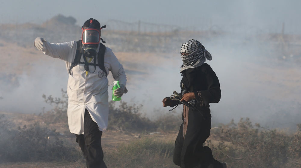 A Palestinian woman runs as Israeli troops fire tear gas during a protest on Friday, August 24 [Ibraheem Abu Mustafa/Reuters]