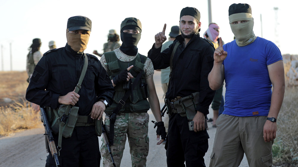 Fighters from Hay'et Tahrir al-Sham are seen outside the villages of al-Foua and Kefraya in July [File: Khalil Ashawi/ Reuters]