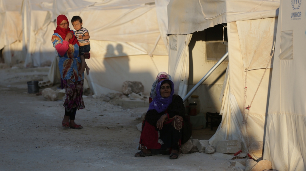 Internally displaced woman sits outside a tent in Idlib province