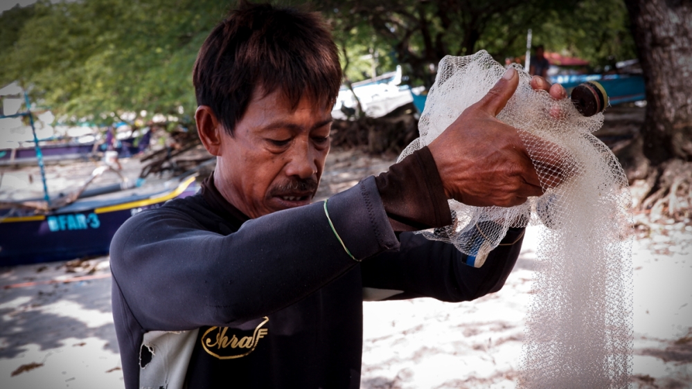 Rony Drio examines his gear before wading into the reefs by his island home to search for aquarium fish [Santiago Arnaiz/Al Jazeera]