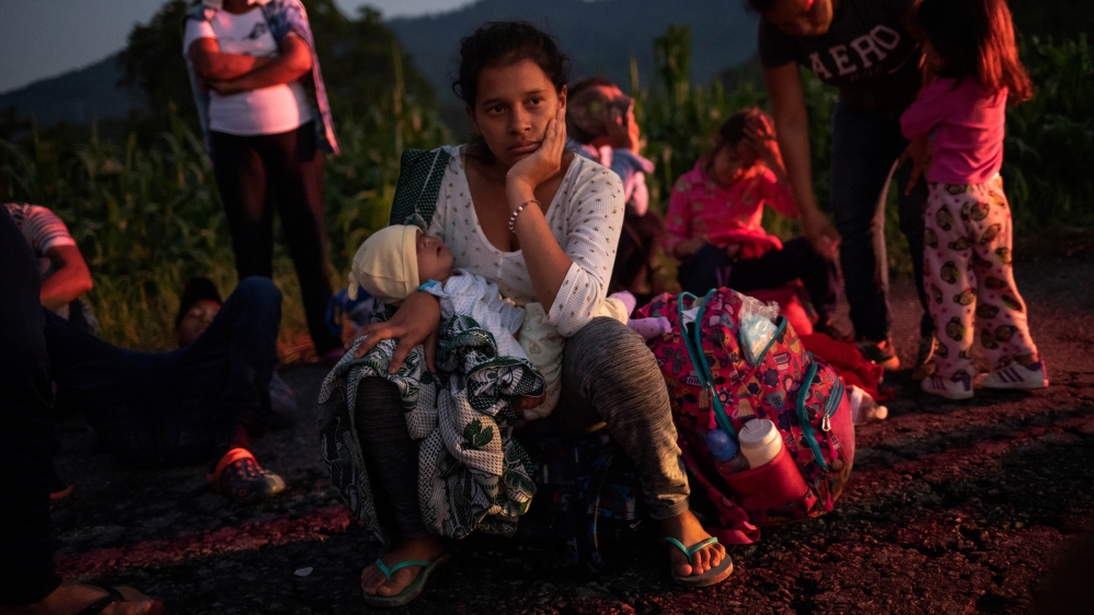 A migrant woman rests roadside with her child while travelling with a caravan of thousands from Central America en route to the United States as they make their way to Mapastepec from Huixtla [Adrees Latif/Reuters]