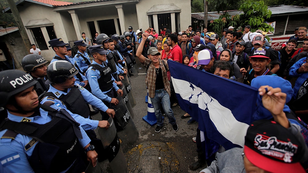 Hondurans stand in front of Honduran police officers blocking the access to the Agua Caliente border with Guatemala as they try to join a migrant caravan heading to the US [Jorge Cabrera/Reuters]