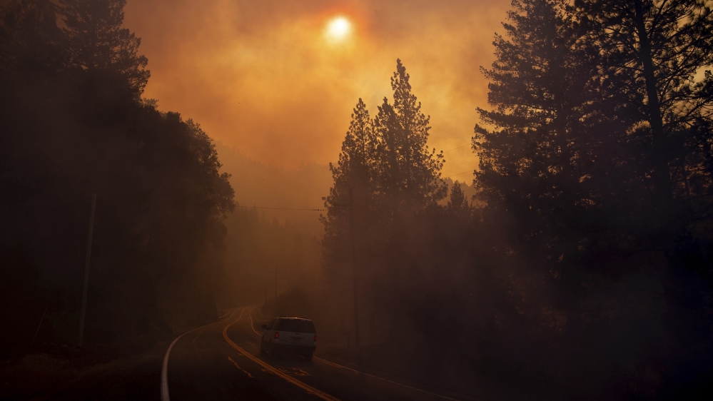 A vehicle drives through smoke from a wildfire near Pulga, California [Noah Berger/AP Photo]