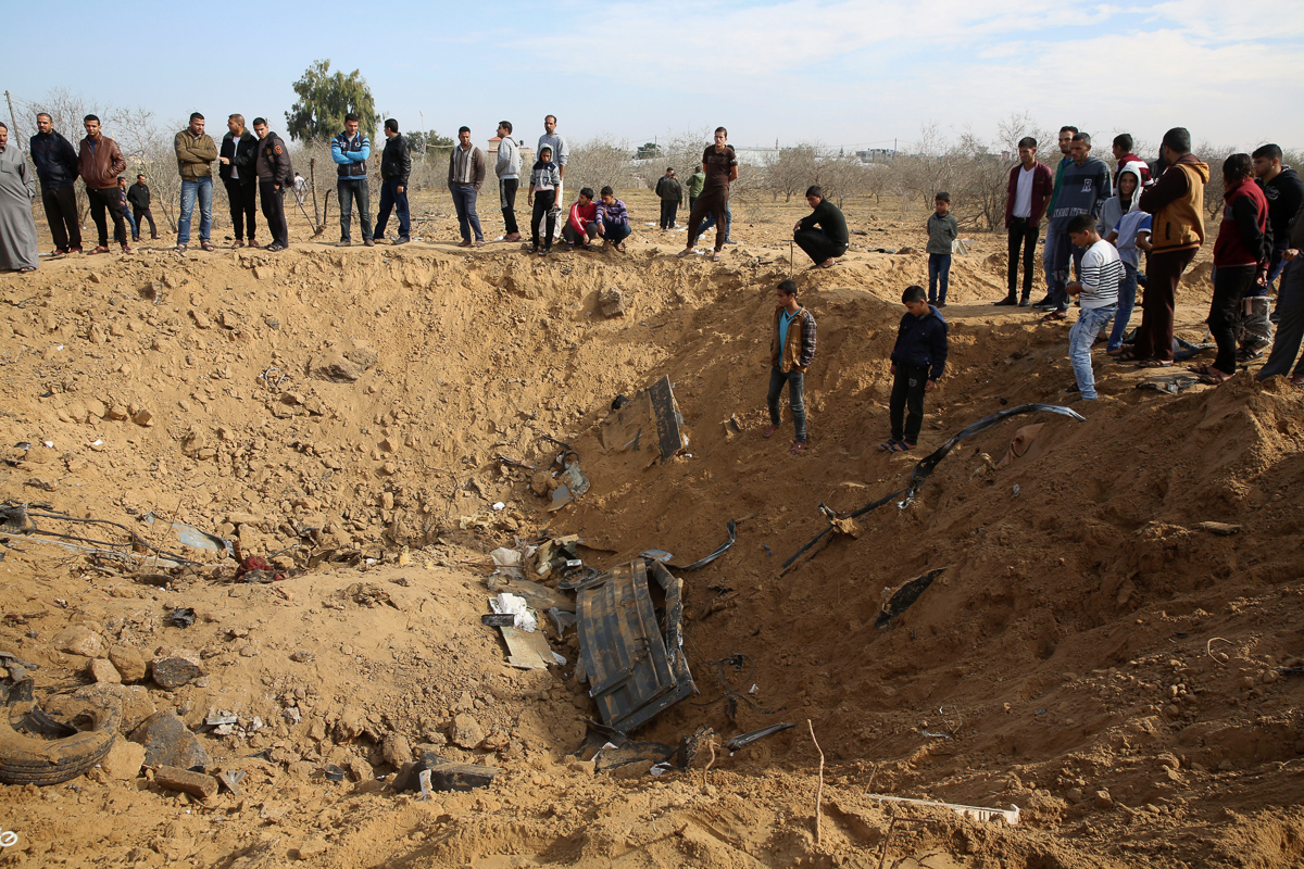 Palestinians inspect a crater and the wreckage of vehicles destroyed by an Israeli raid that killed seven Hamas Palestinian militants late Sunday, east of Khan Younis, southern Gaza Strip, Monday, Nov