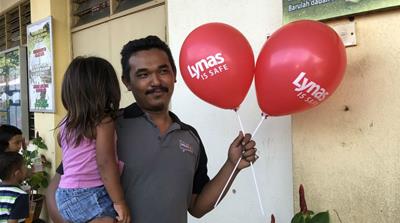 Lynas has gone on a publicity offensive as Malaysia's government reviews its operations. Here, a man and his child attend a Lynas-sponsored event at a local school [Florence Looi/Al Jazeera]