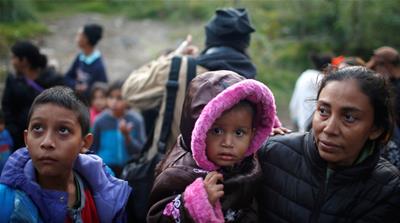 Migrants from Honduras, part of a caravan of thousands from Central America trying to reach the United States, stand next to the border fence as they prepare to cross it illegally, in Tijuana