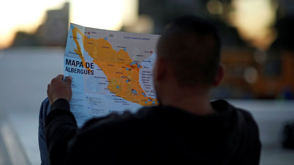 A man holds a map as he waits to leave with a new caravan of migrants, set to head to the United States, at El Salvador del Mundo Square in San Salvador [Jose Cabezas/Reuters]