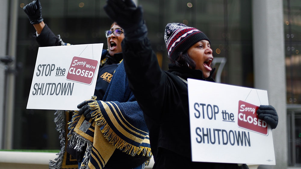 Cheryl Monroe (right), a Food and Drug Administration employee, and Bertrice Sanders, a Social Security Administration employee, rally to call for an end to the partial government shutdown [Paul Sancya/AP Photo] 