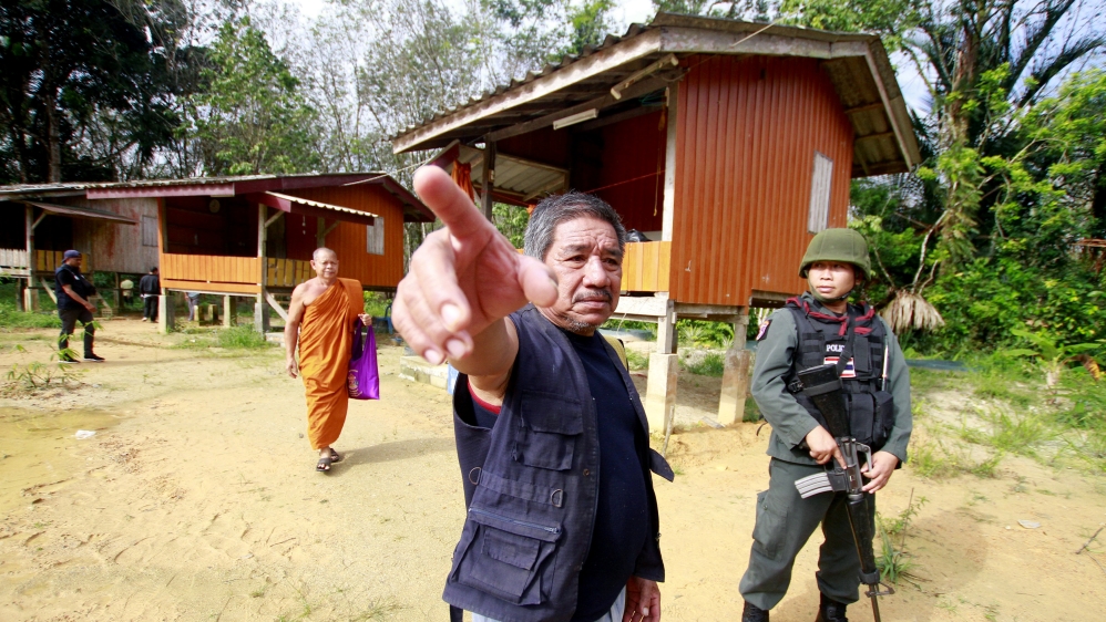 MilitaMilitary police officers and a buddhist monk are seen at a temple where unknown gunmen shot dead two Buddhist monks and injured two others on Friday in Su-ngai Padi district in the southern prov