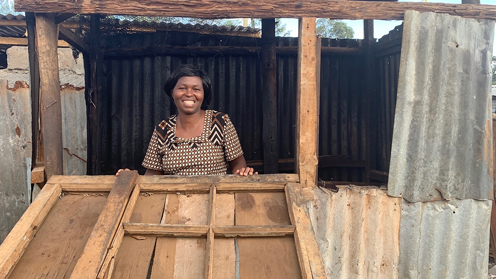 Beverlan Muhonja, another member of the chama, stands at her stall in Kawangware, from where she sells chips and mandazi, a type of doughnut [William Worley/Al Jazeera]
