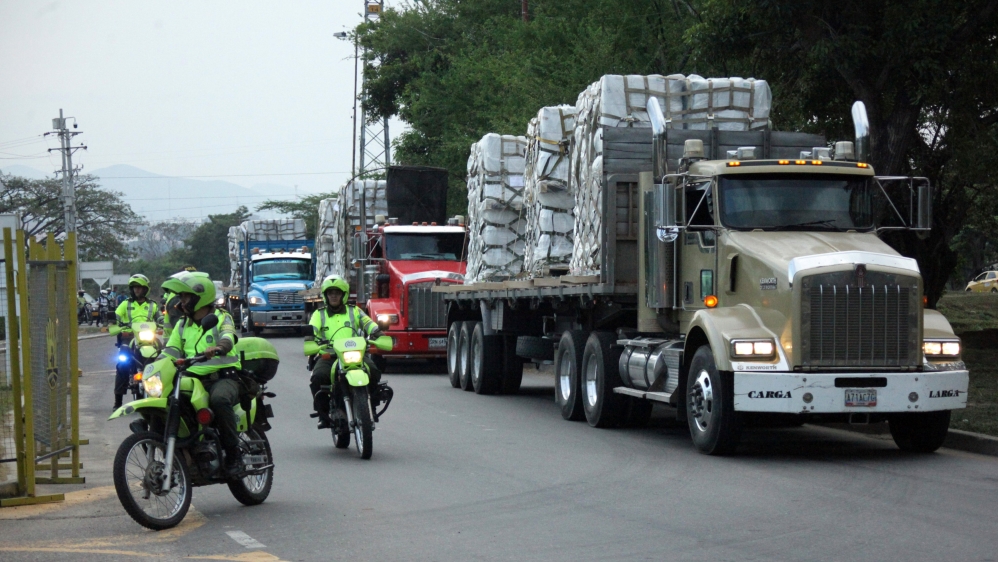 Police officers escort trucks as they arrive at a warehouse, where international humanitarian aid for Venezuela will be stored [Carlos Ramirez/Reuters]