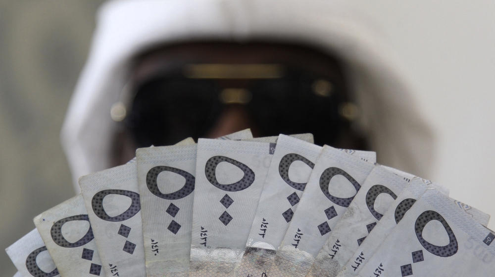 A Saudi man poses with Saudi riyal banknotes