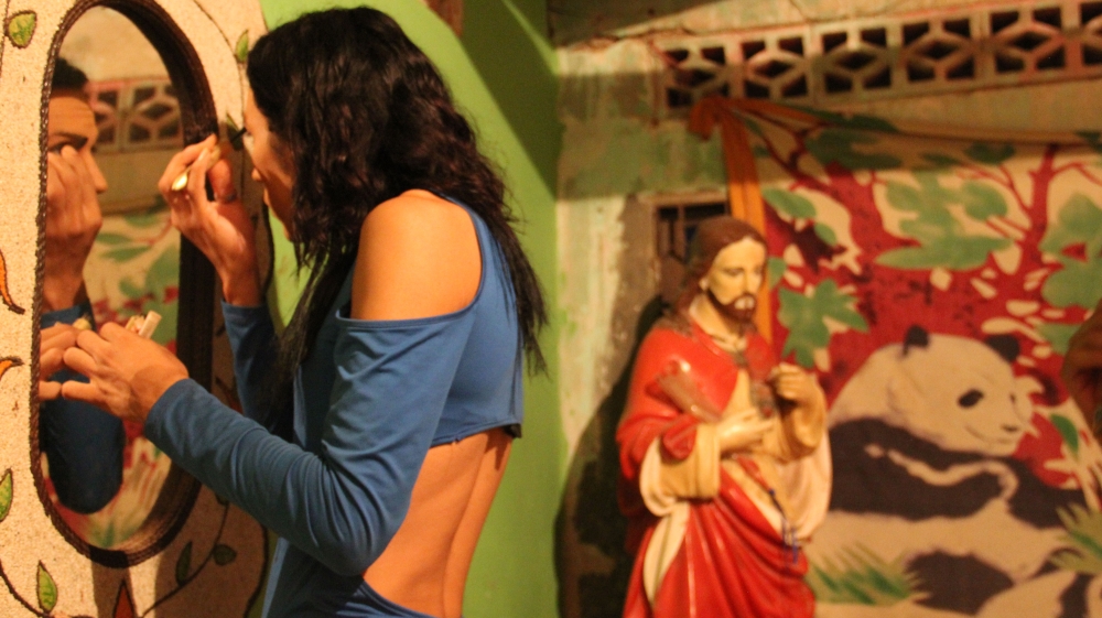 A woman puts on her makeup in Madonna Badillo's home [Steven Grattan/Al Jazeera] 