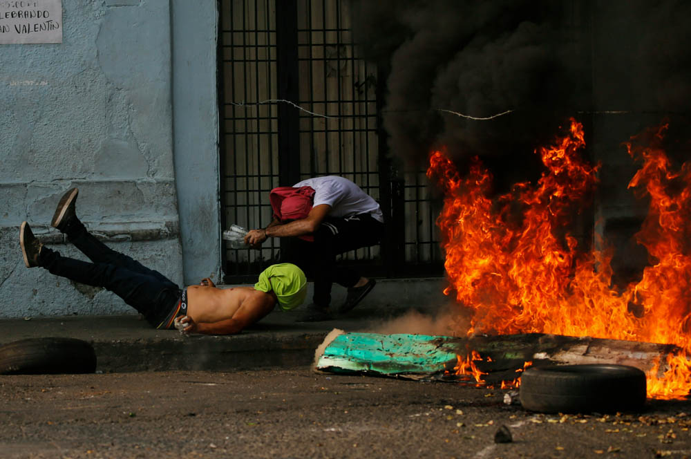 A demonstrator, left, falls after getting caught in a strand of barbed wire during clashes with the Bolivarian National Guard in Urena, Venezuela, near the border with Colombia, Saturday, Feb. 23, 201