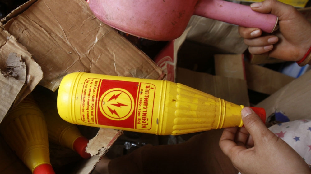 A Cambodian vendor with a bottle of sulphuric acid from a box at her shop near the Cambodia-Thai border [File: Heng Sinith/AP Photo]