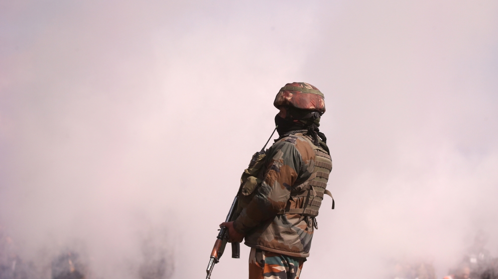 An Indian soldier stands guard as smoke billows from the wreckage of Indian Air Force''s helicopter after it crashed in Budgam