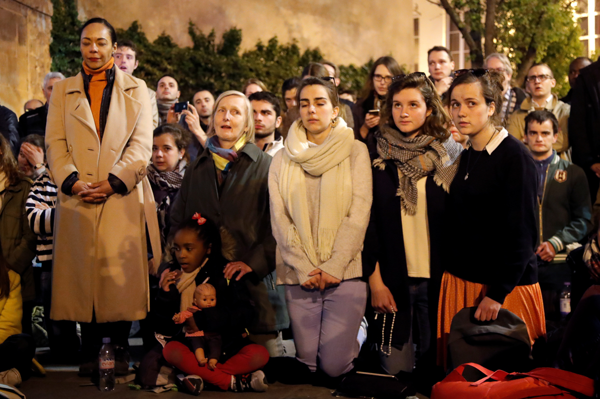 People pray and sing religious songs next to Notre Dame Cathedral after a fire broke out, in Paris, France April 15, 2019. REUTERS/Charles Platiau