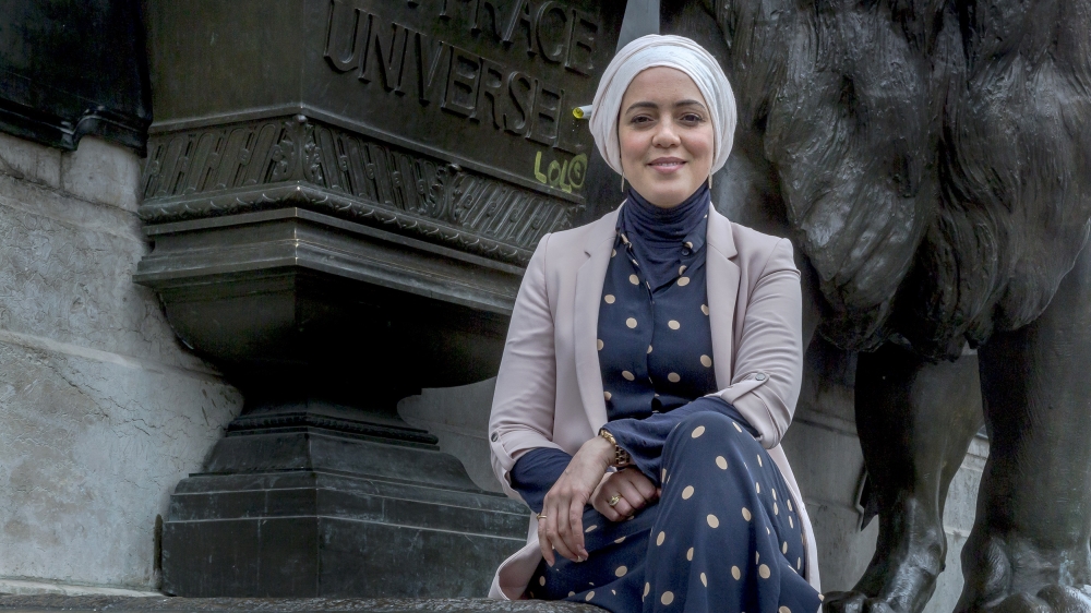 Freelance journalist Nadiya Lazzouni poses for a photo underneath the Monument a la Republique where the phrase universal suffrage is engraved in Place de la Republique in Paris [Omar Havana/Al Jazeera] 