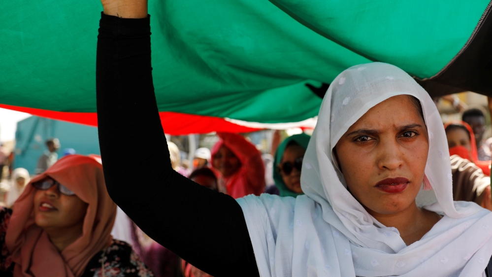 Protesters hold a Sudanese flag as they march outside the army headquarters [Umit Bektas/Reuters]