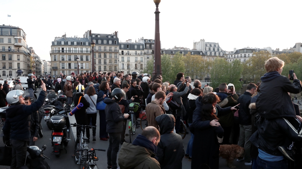 People watch from a bridge as the Notre Dame Cathedral burns in Paris [Benoit Tessier/Reuters] 