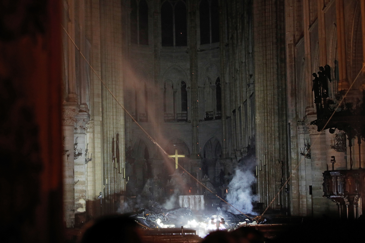 Smoke rises around the altar in front of the cross inside the Notre Dame Cathedral as a fire continues to burn in Paris, France, April 16, 2019. REUTERS/Philippe Wojazer/Pool