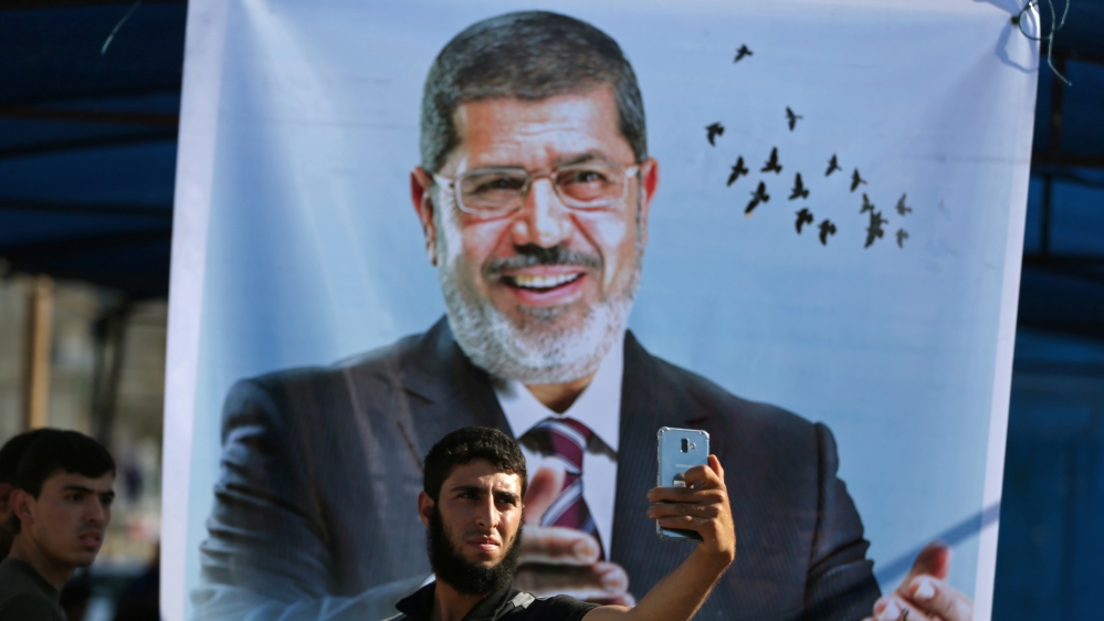 Palestinian man takes a selfie in front of a poster depicting former Egyptian president Mohamed Mursi at a mourning tent for Mursi, in Khan Younis in the southern Gaza Strip