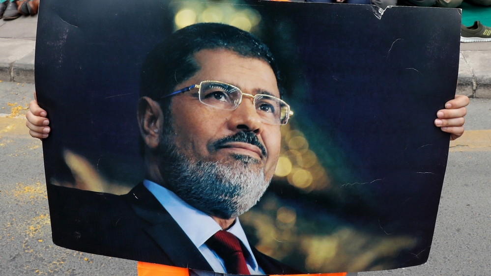A boy holds a picture of the Egyptian President Mohamed Morsi during a symbolic funeral prayer on June 18,2019 in front of the embassy in Ankara. Thousands joined in prayer in Istanbul on Tuesday for