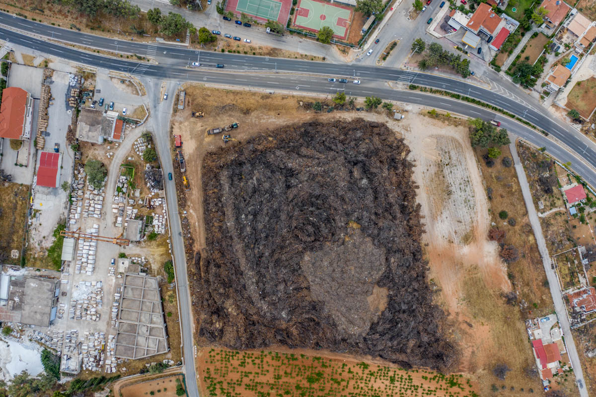 Locals say the clean-up operation is months behind schedule and warn that a plot of land in the area containing a bulky mass of burned branches and trunks is a time bomb for a new fire.