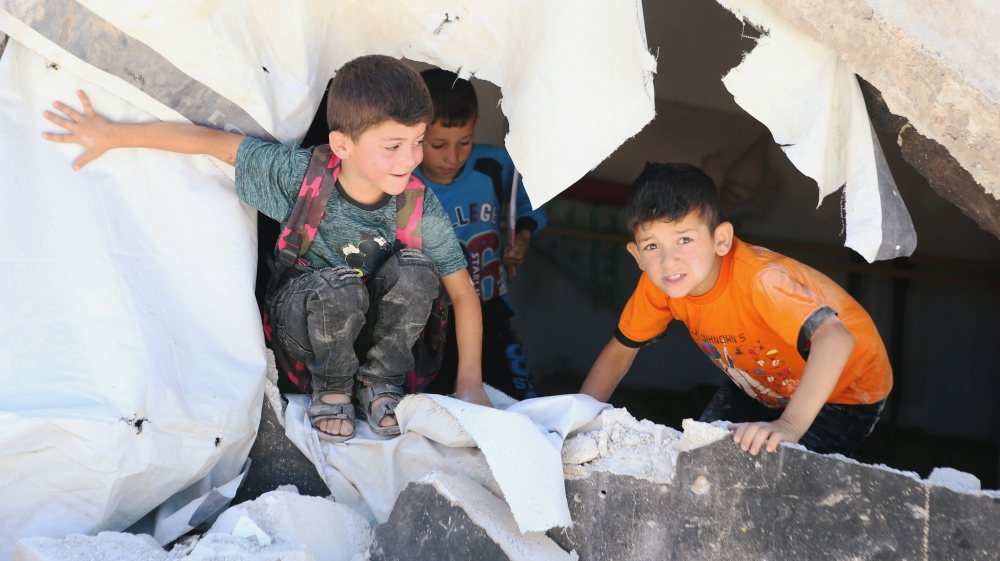 Syrian refugee kids play on rubble of dismantled concrete huts at a makeshift Syrian refugee camp in the Lebanese border town of Arsal