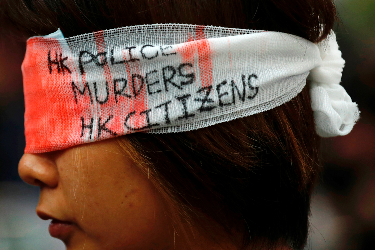 An anti-extradition bill protester covers her eye with a gauze during a mass demonstration after a woman was shot in the eye during a protest at Hong Kong International Airport, in Hong Kong, China Au