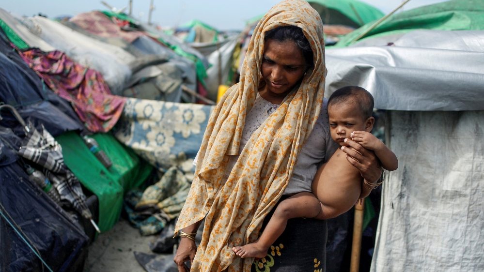 A Rohingya Muslim woman holds a baby as they wait to cross the border to go to Bangladesh, in a temporary camp outside Maungdaw, northern Rakhine state, Myanmar November 12, 2017.