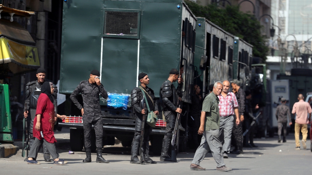 Police watch as people cross the street in Ramses Square in Cairo