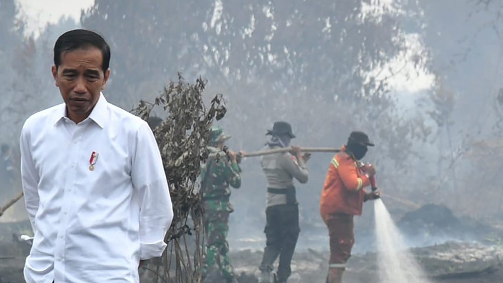 This handout picture taken on September 17, 2019 shows Indonesian President Joko Widodo inspecting the damages from the ongoing forest fires in Pekanbaru. - Indonesia has arrested nearly 200 people ov