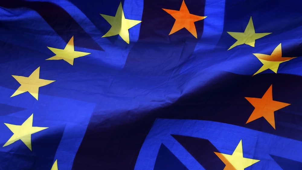A pro EU protestor waves flags opposite the House of Parliament in London, Thursday, April 4, 2019