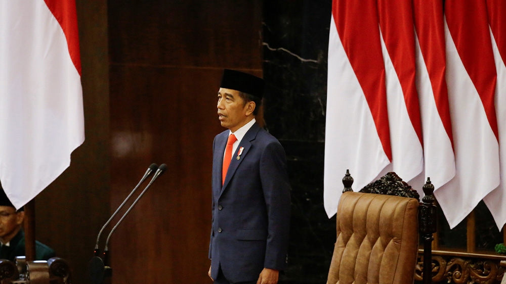 Indonesian President Joko Widodo stands in front of an Indonesian flag