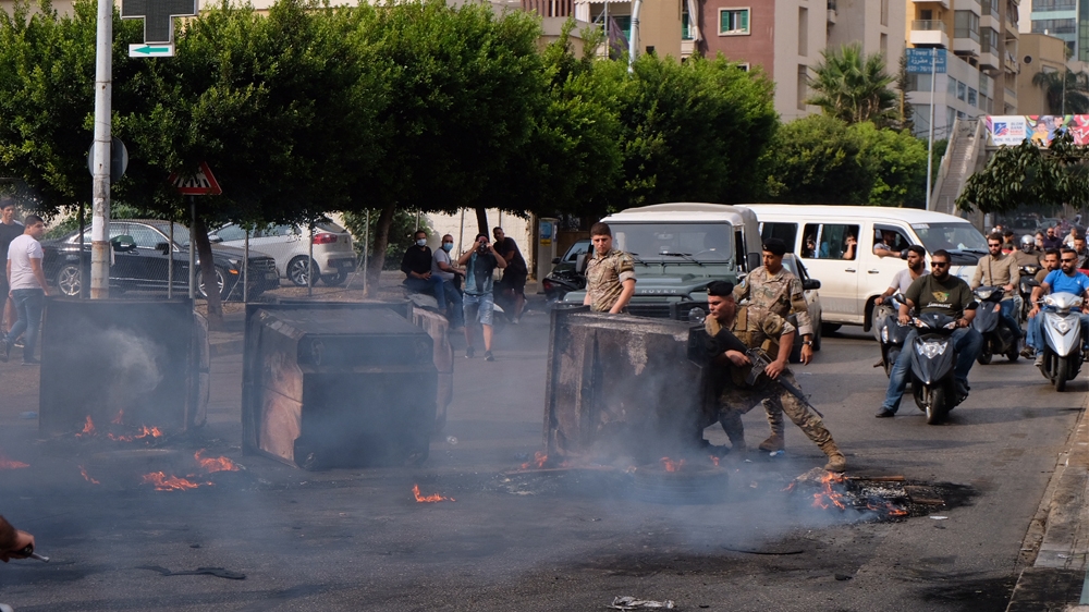 A soldier tried to clear a path through smoldering garbage bins and flaming tires on the outskirts of downtown Beirut [Timour Azhari/Al Jazeera]