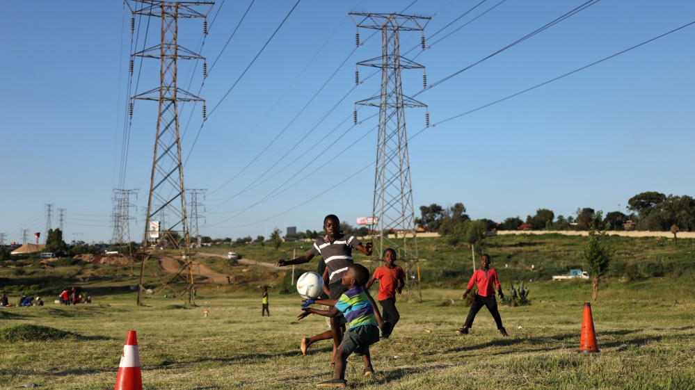Boys use traffic cones as goal posts as the play soccer below electricity pylons in Soweto