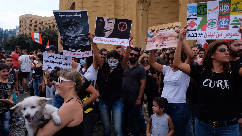 Protestors hold placards calling out the political establishment in downtown Beirut [Timour Azhari/Al Jazeera]