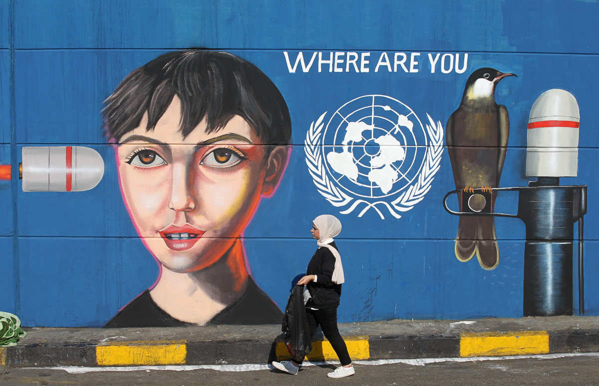 An Iraqi woman walks along a wall covered with a mural painting during an anti-government demonstration in the capital Baghdad''s Tahrir square on November 4, 2019. - Iraqi security forces fired live r
