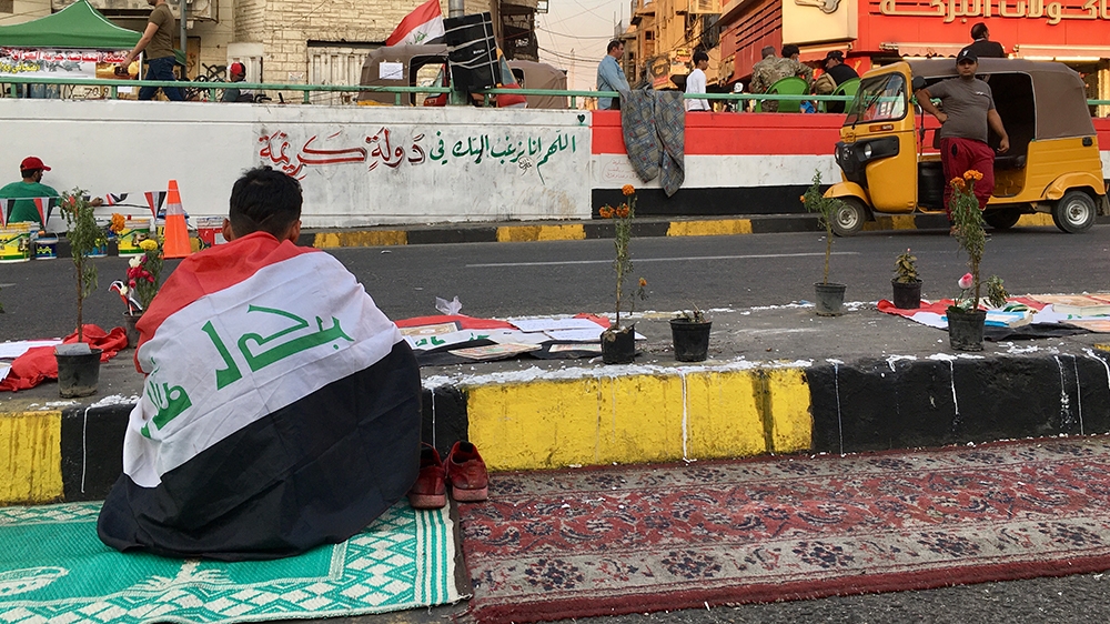 A young man reads the Quran in front of a memorial for the dead protesters [Sofia Barbarani/Al Jazeera]
