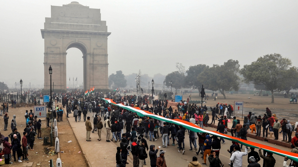 Demonstrators hold a tricoloured flag in front of the India Gate during a demonstration against what they say was an alleged police action conducted during recent protests against a new citizenship la