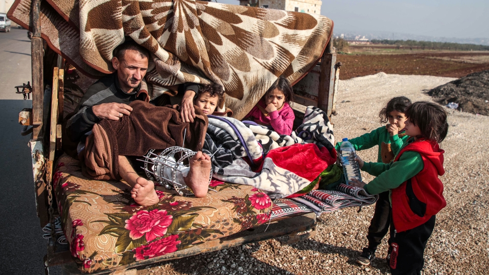 An injured man sits alongside children in the back of a truck as part of a convoy of vehicles of people from the south of Idlib province fleeing bombardment by the government and its allies on the nor