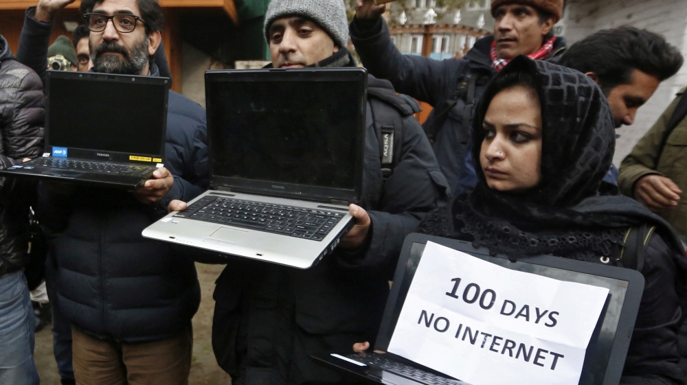 Kashmiri journalists display laptops and placards during a protest demanding restoration of internet service, in Srinagar